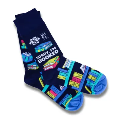 Navy blue socks featuring colourful bookshelves and white text stating "Sorry, I'm booked".