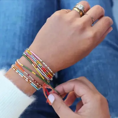 A wrist full of colourful braided bracelets.