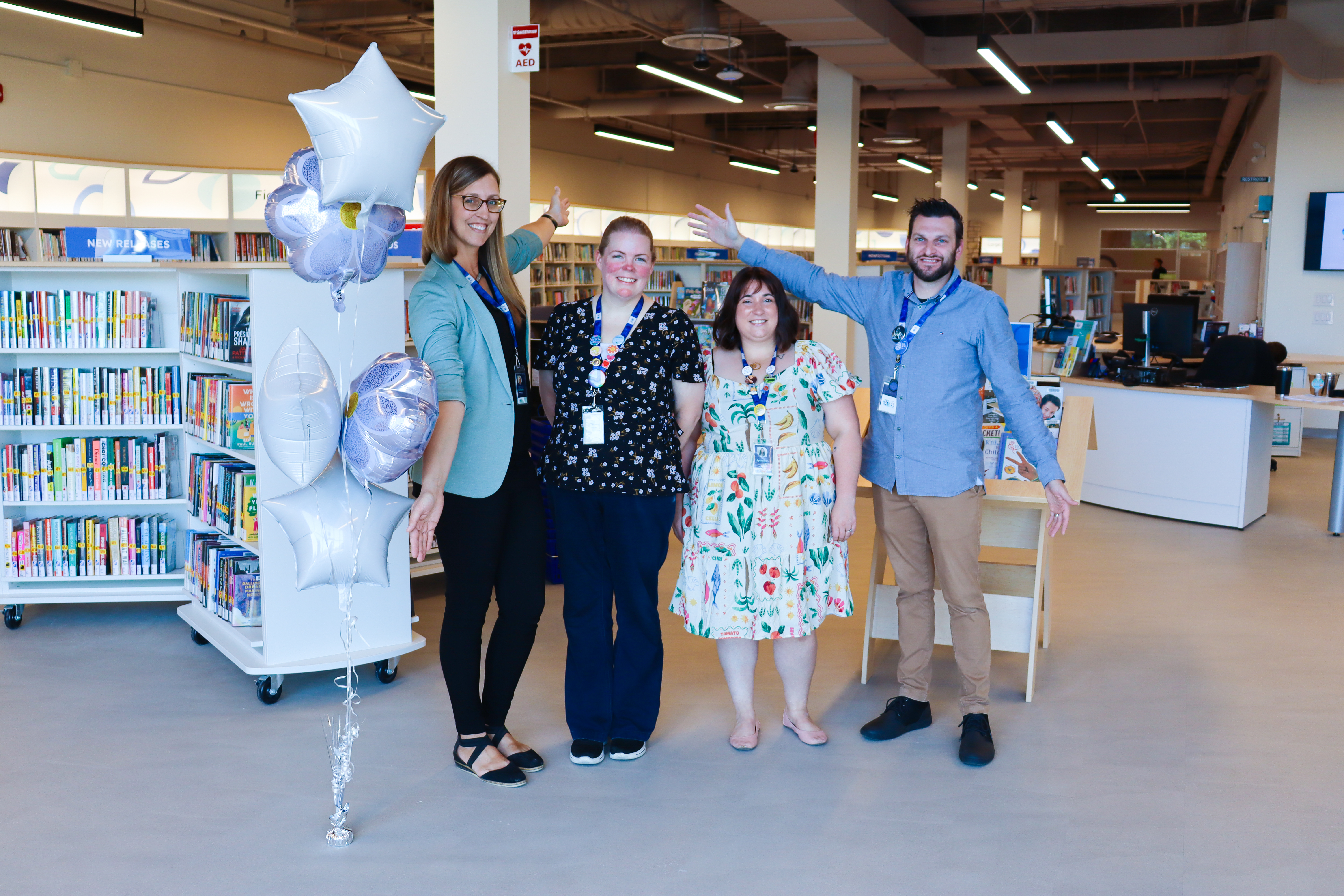 Four Merritt Branch staff members stand in a line welcoming customers to the Merritt Branch on opening day.