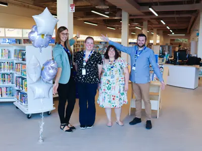 Four Merritt Branch staff members stand in a line welcoming customers to the Merritt Branch on opening day.