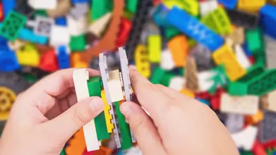 Young hands snapping LEGO pieces together.