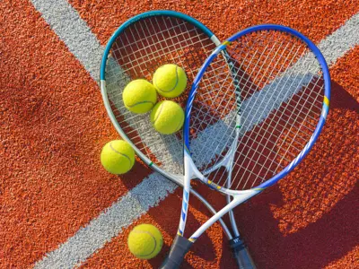 Tennis rackets and tennis balls laying on a tennis court.