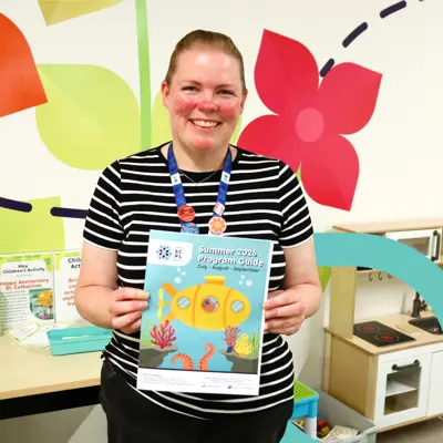 Library staff member holding up a program guide.