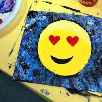 A heart eyes emoji painting on a crafting table.