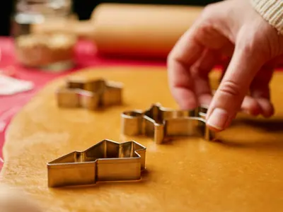 Hand pressing a gingerbread man cookie cutter into rolled out cookie dough.