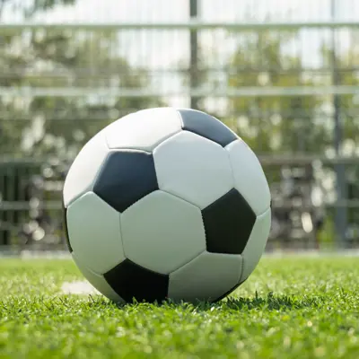 A soccer ball sitting on a field in front of a soccer net.