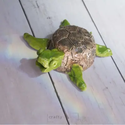 A painted clay turtle sitting on a porch.