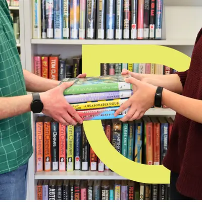 An unidentified individual hands a stack of books to another person.