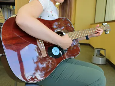 Woman sitting and holding a guitar.