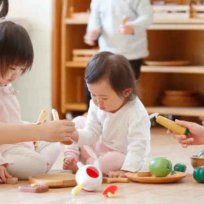 Two young children playing on the floor with two women.