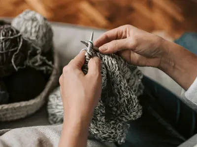 Hands knitting grey yarns.