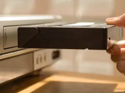 A hand putting a VHS tape into a VHS player.