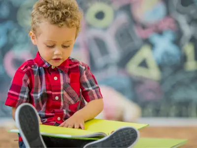 A little boy reding a book in his lap.