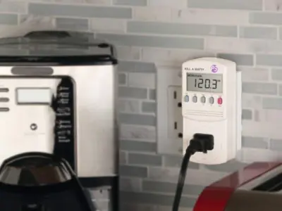 Kill A Watt device pulled into an outlet beside a coffee maker.