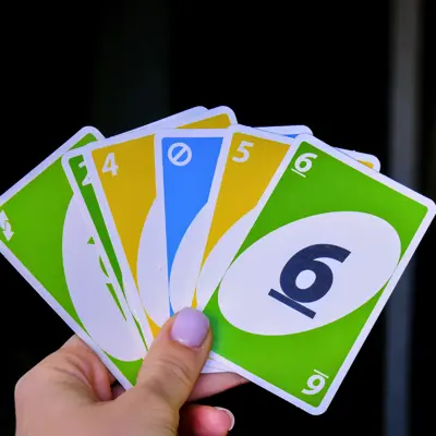 A hand holding a series of colourful Uno cards.