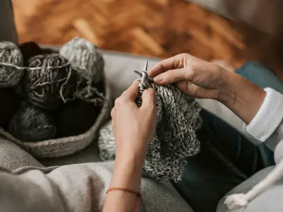 Hands knitting grey yarn.